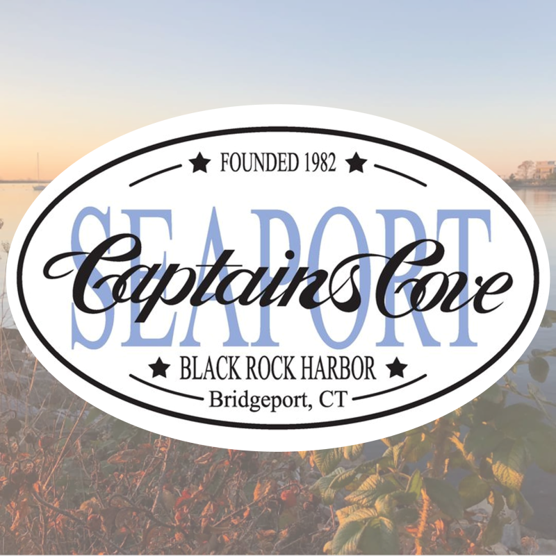 A logo for the Captain's Cove Seaport, Restaurant, Marina, and Bar. The logo sits in front of a picturesque sunset of the marina. 