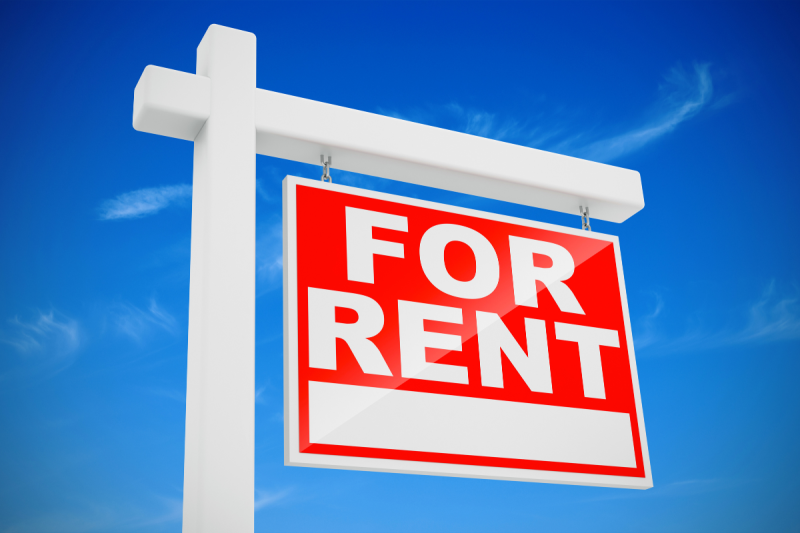 Picture of an angled "for rent" sign with a bright blue sky in the background