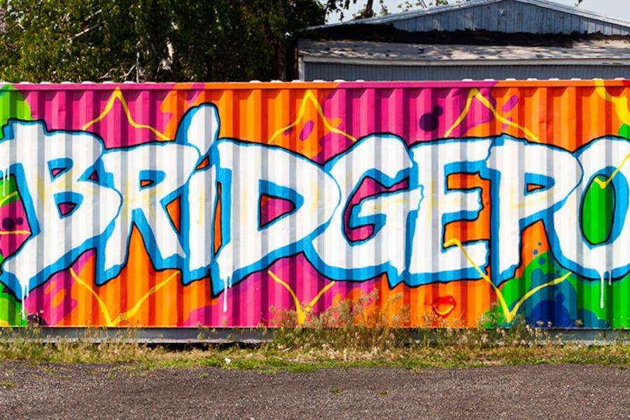 A banner image of a storage container artfully painted with many different colors in an abstract form. A large blue, yellow, and red heart on the left and the name "Bridgeport" across the center of the container. 