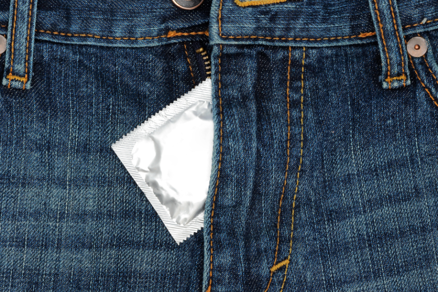 A condom package tucked into a blue jeans zipper