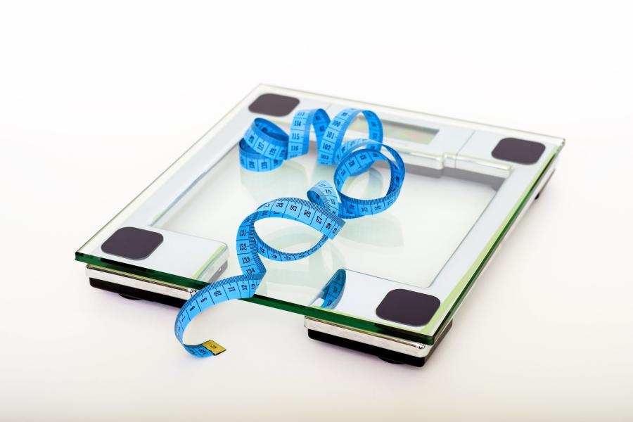 A clear glass scale with a blue tape measure on top of it