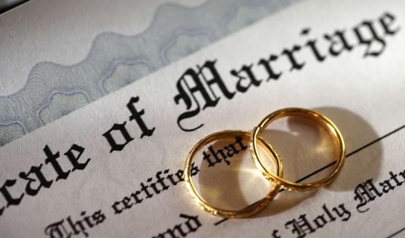 Close up of a marriage certificate with two gold wedding bands on top