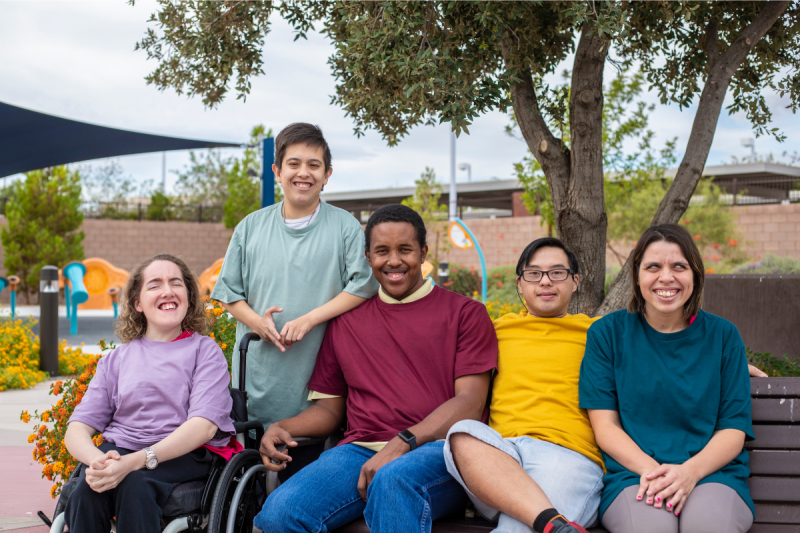 A group of 5 individuals with disabilities smiling