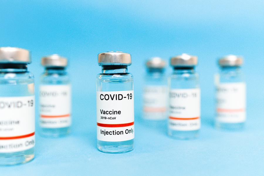 Photo of six COVID19 vaccine vials on a blue background