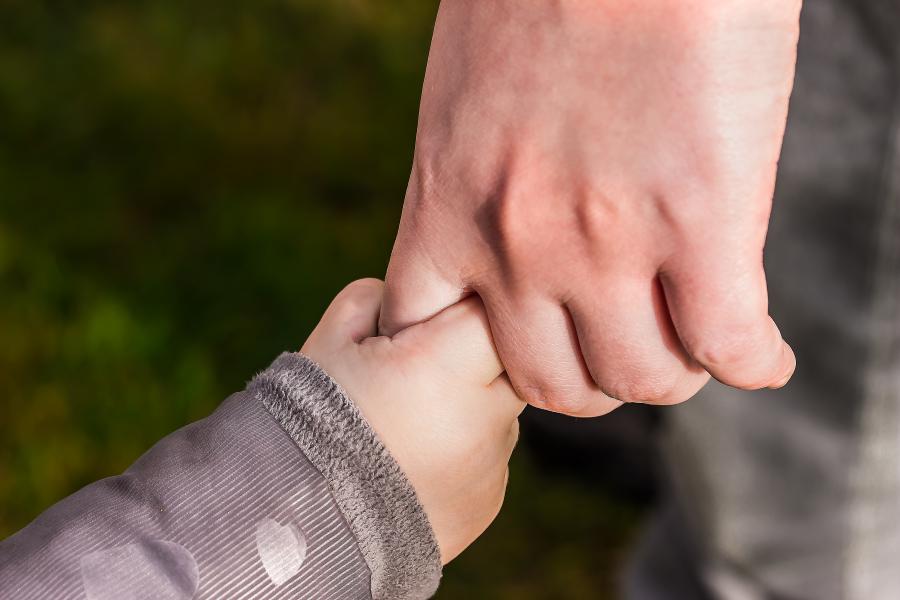 Close up of child and adult holding hands