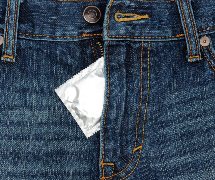 A condom package tucked into a blue jeans zipper