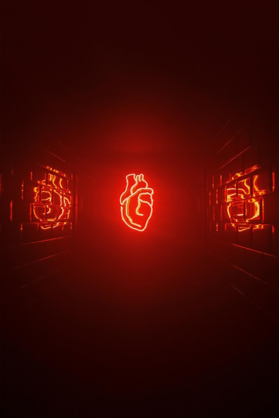 A red neon sign of an anatomical heart on the back wall of a dark corridor